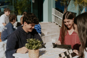 Grupo de estudiantes jugando a un juego de mesa al aire libre en la residencia universitaria ONE Sevilla, disfrutando de un momento de convivencia